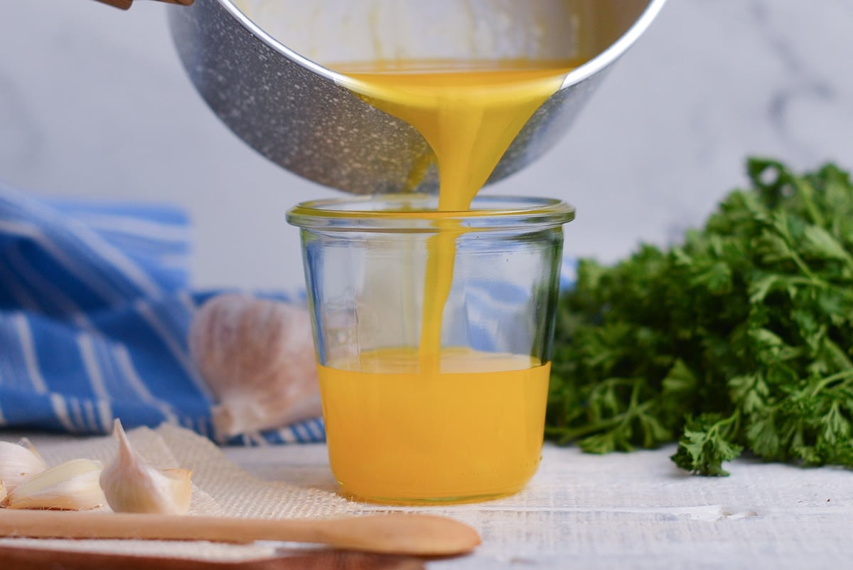 pouring clarified butter into a glass jar