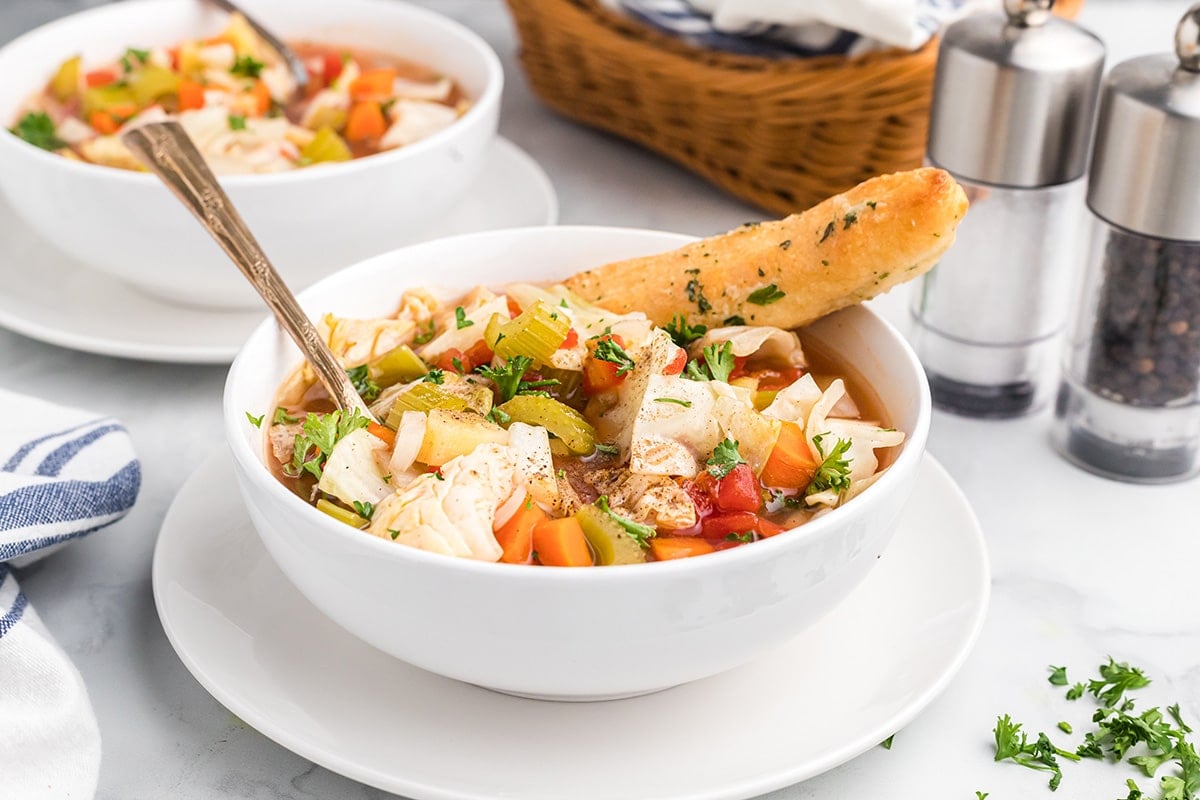 angled shot of healthy cabbage soup with breadstick