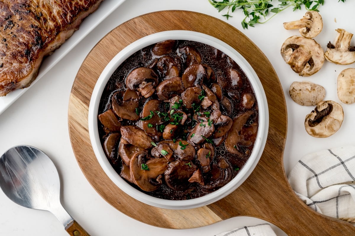 mushroom sauce for steak in a white serving bowl with parsley on top