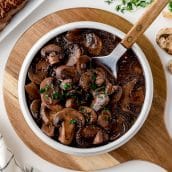 overhead of a spoon in a bowl of mushrooms