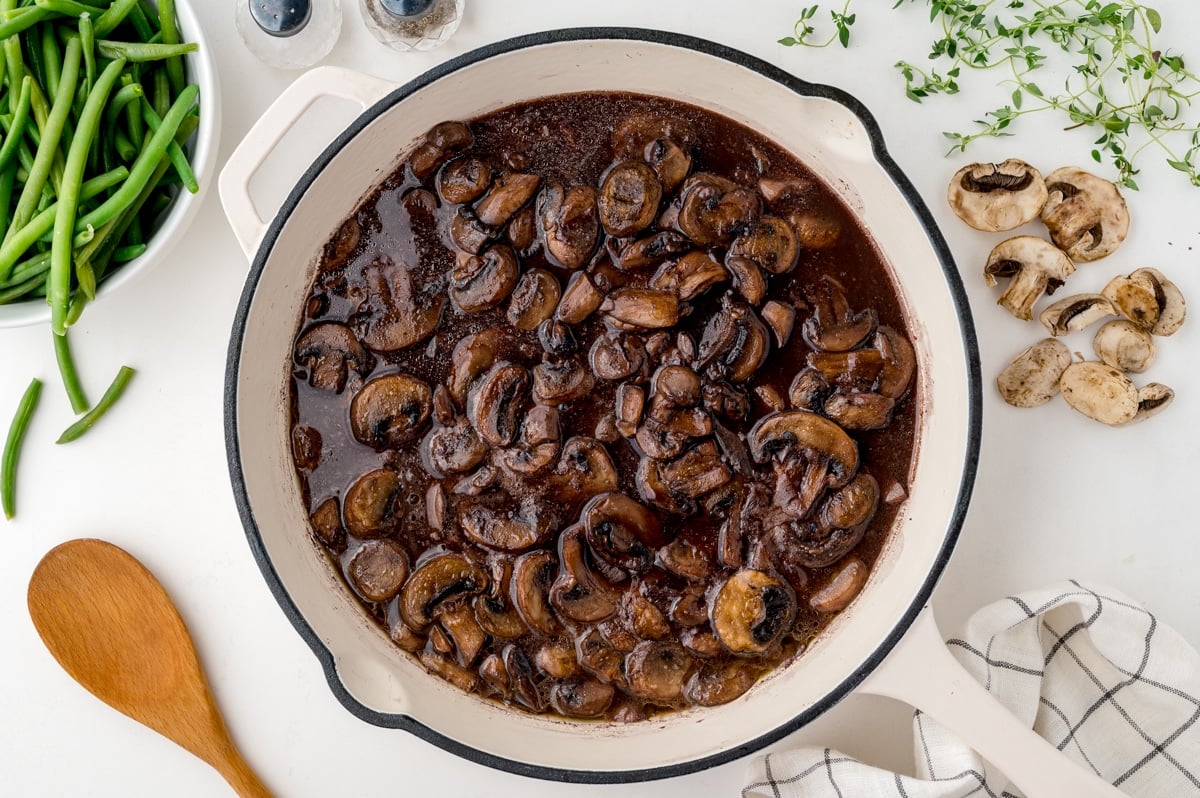 overhead of red wine mushroom sauce in a white skillet