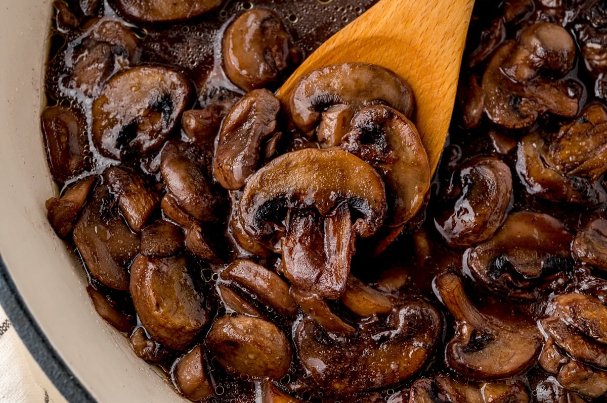 wooden spatula with mushrooms in a skillet