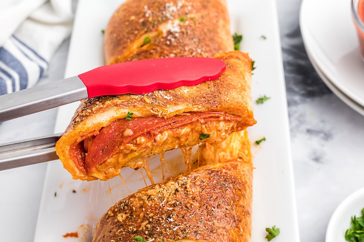 tongs grabbing piece of stromboli