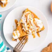 overhead slice of pumpkin cheesecake with caramel and whipped cream