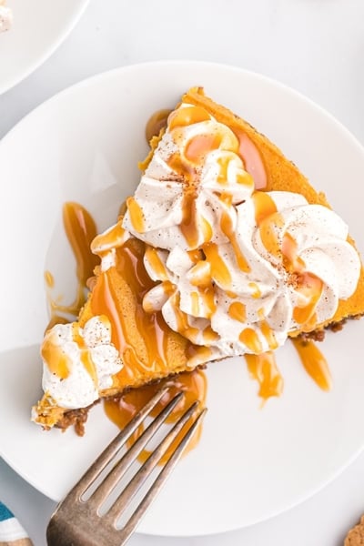 overhead slice of pumpkin cheesecake with caramel and whipped cream