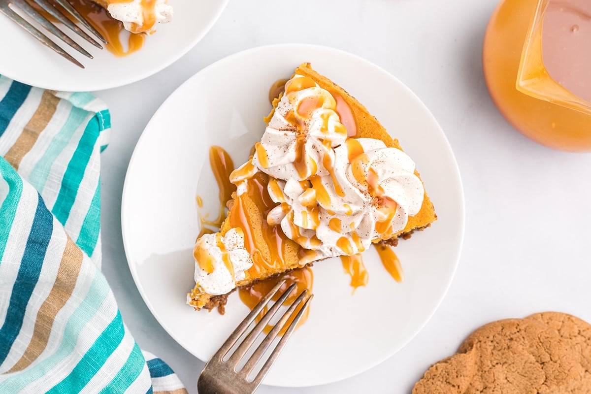 overhead slice of pumpkin cheesecake with caramel and whipped cream