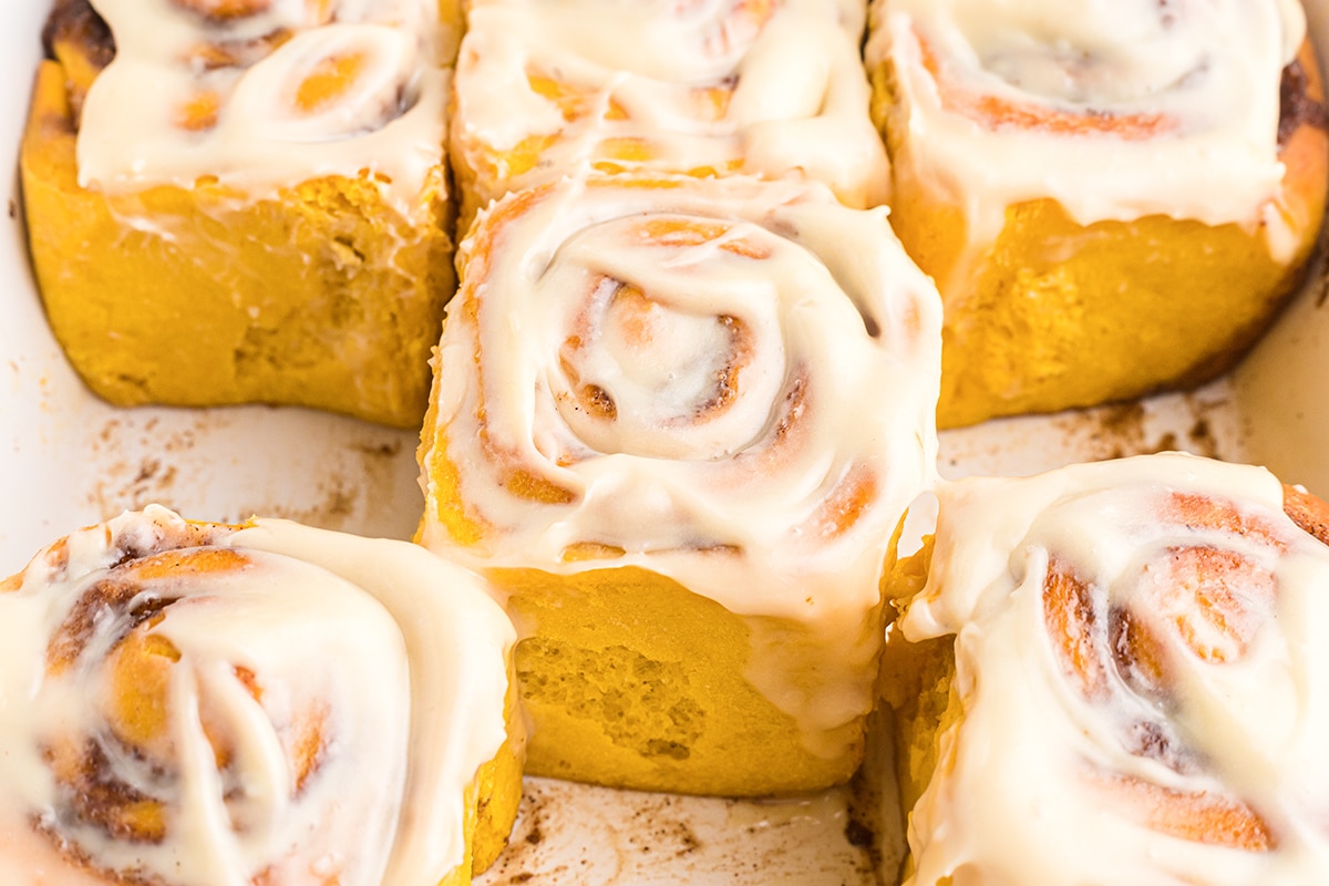 close up of a frosted pumpkin cinnamon roll