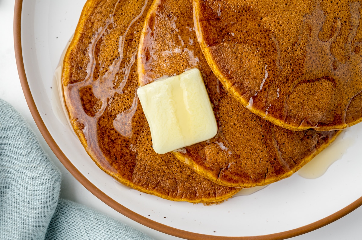 pad of butter on pancakes with syrup