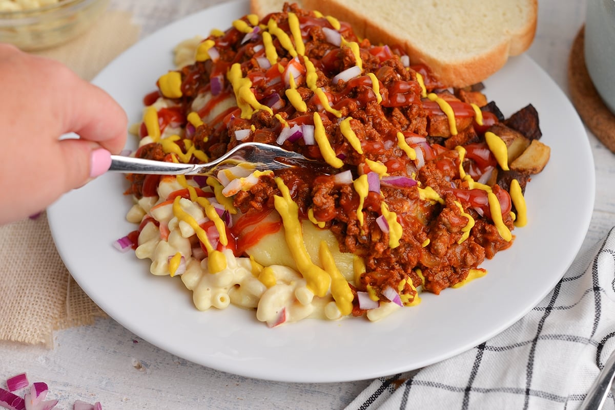 fork digging into a garbage plate with hot sauce