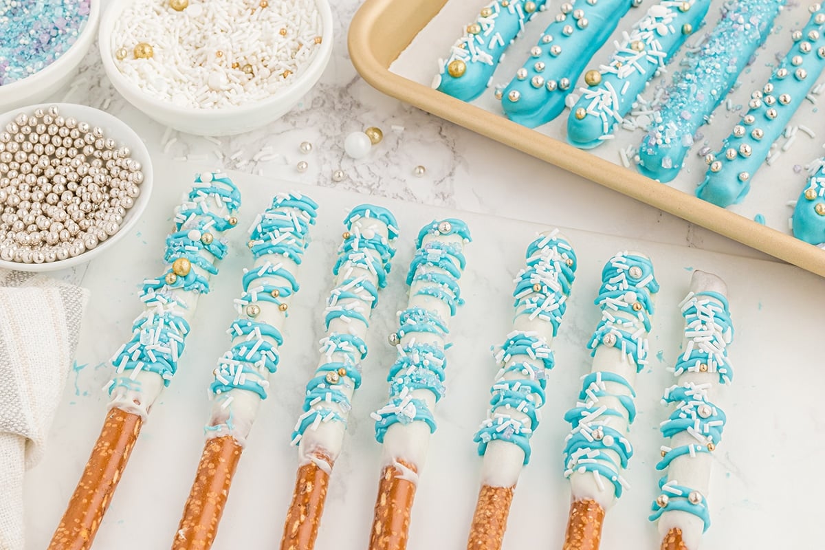chocolate covered pretzel rods lined up on parchment paper