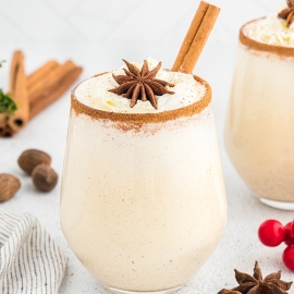glass of eggnog with cinnamon stick and whipped cream