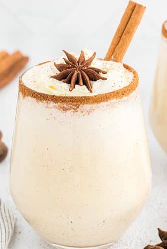 glass of eggnog with cinnamon stick and whipped cream