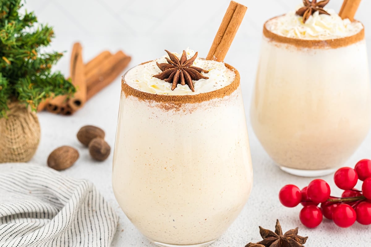 glass of eggnog with cinnamon stick and whipped cream