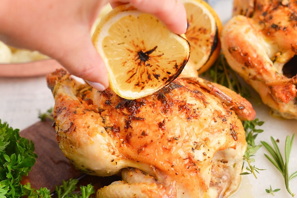 charred lemon spritzing onto a game hen