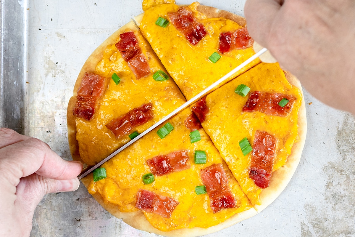 knife slicing bacon cheddar flatbread