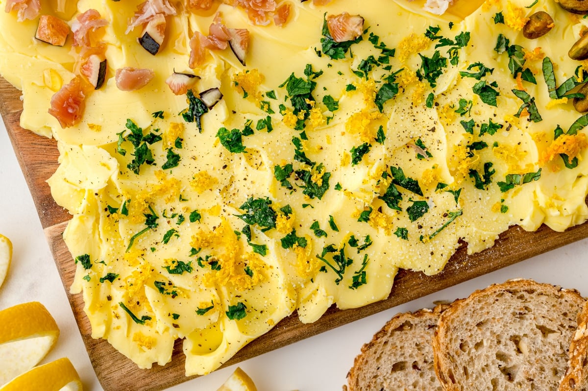 close up of fresh herbs and zest on a butter board