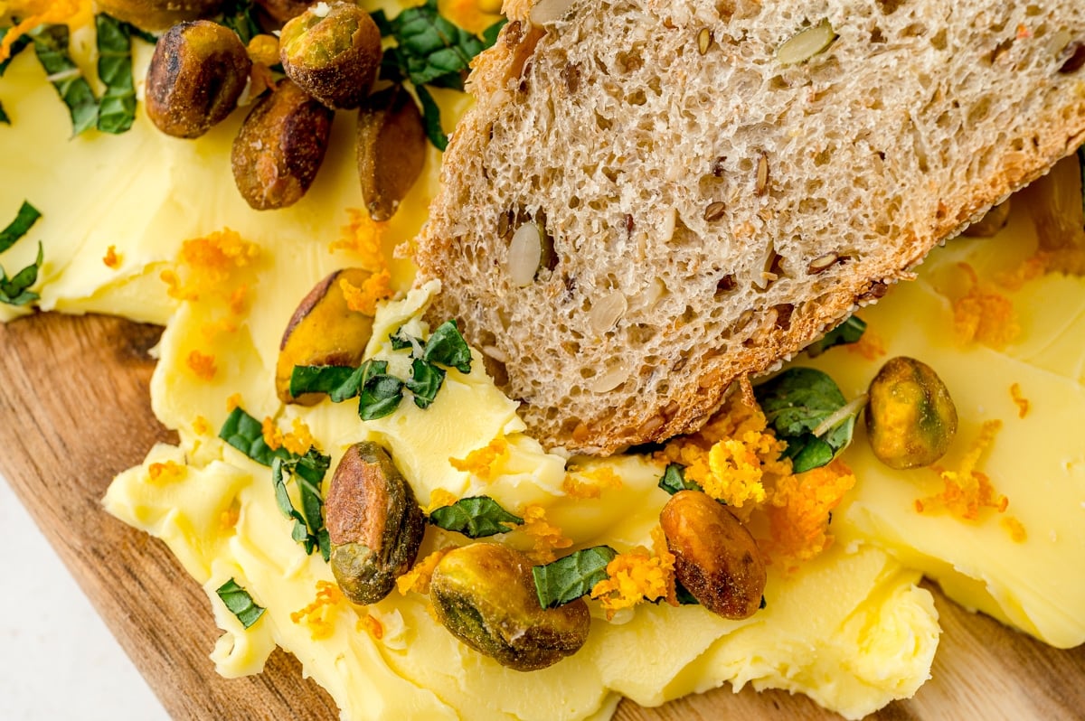 seeded bread dipping into a butter board