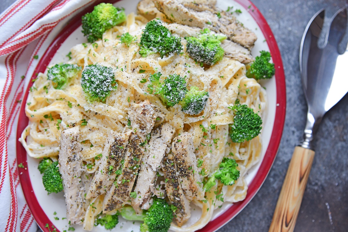 overhead of broccoli chicken alfredo on a red serving platter