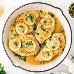 chicken in piccata sauce in a white cast iron skillet
