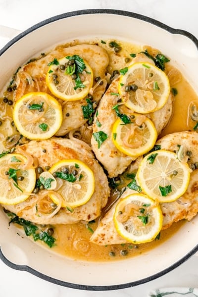 chicken in piccata sauce in a white cast iron skillet