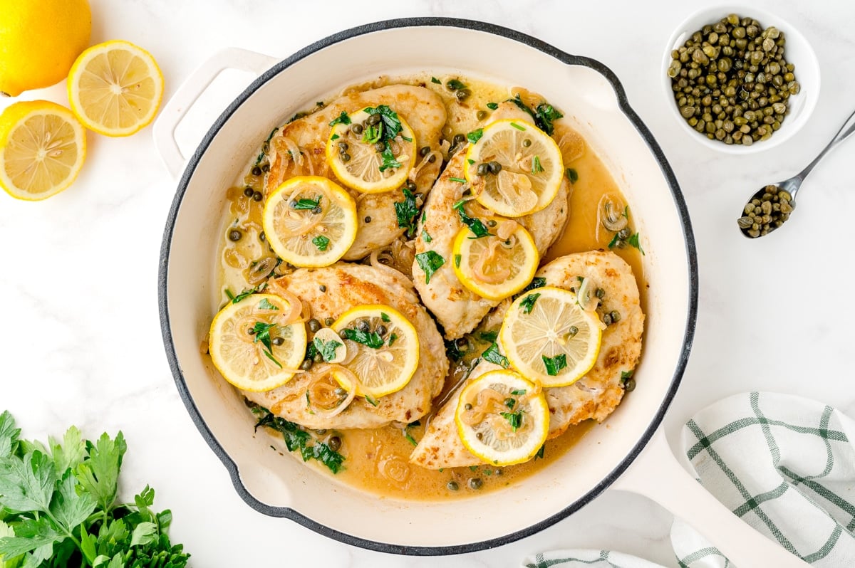 chicken in piccata sauce in a white cast iron skillet