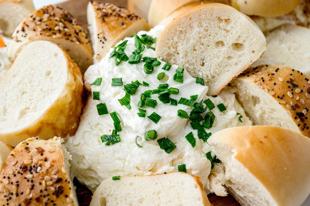 bagel dipping into chive cream cheese