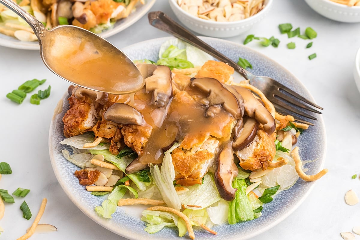 spooning gravy over chinese almond chicken