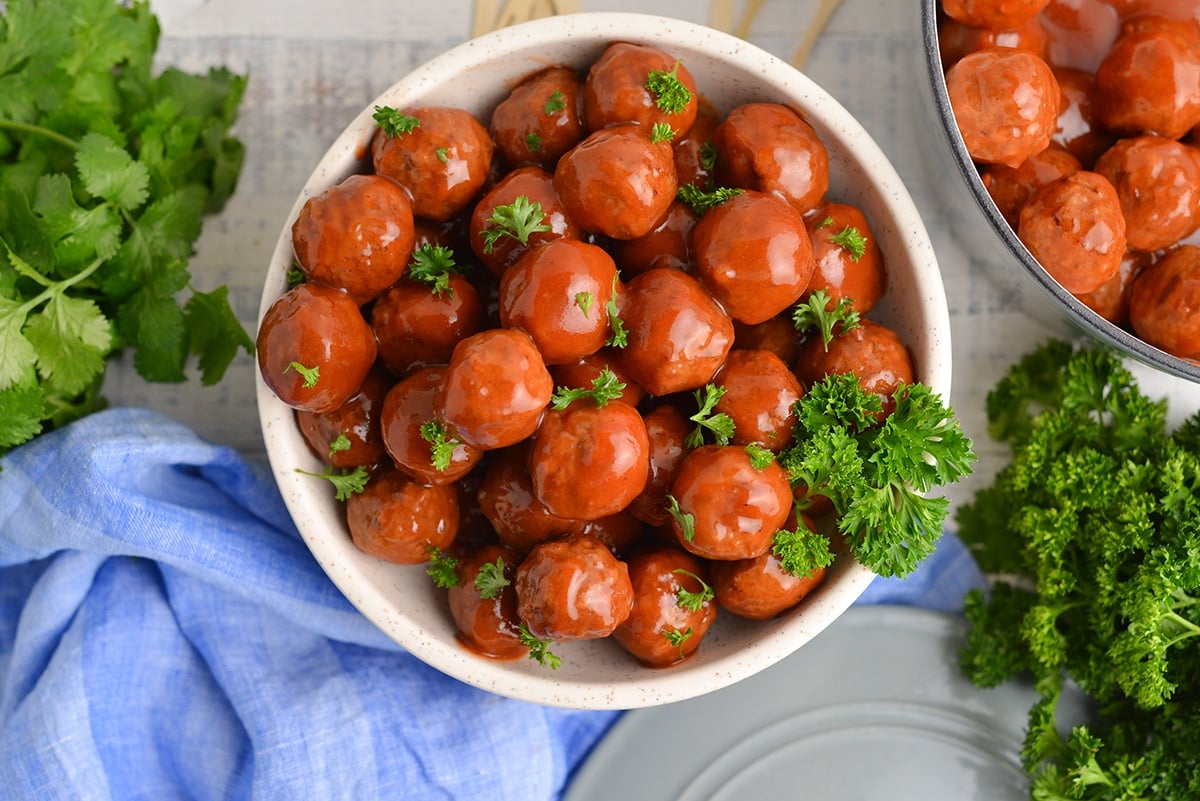 grape jelly meatballs in a white speckled serving bowl