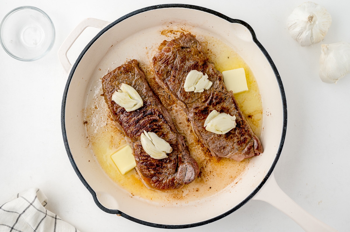 seared steak with butter and garlic in a cast iron pan