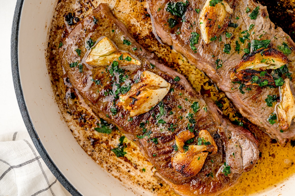 close up of a seared steak with garlic and butter