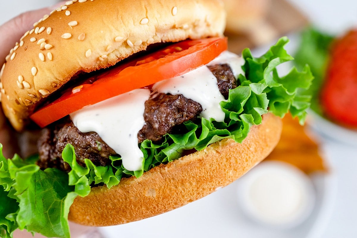 close up of hand holding a ranch burger