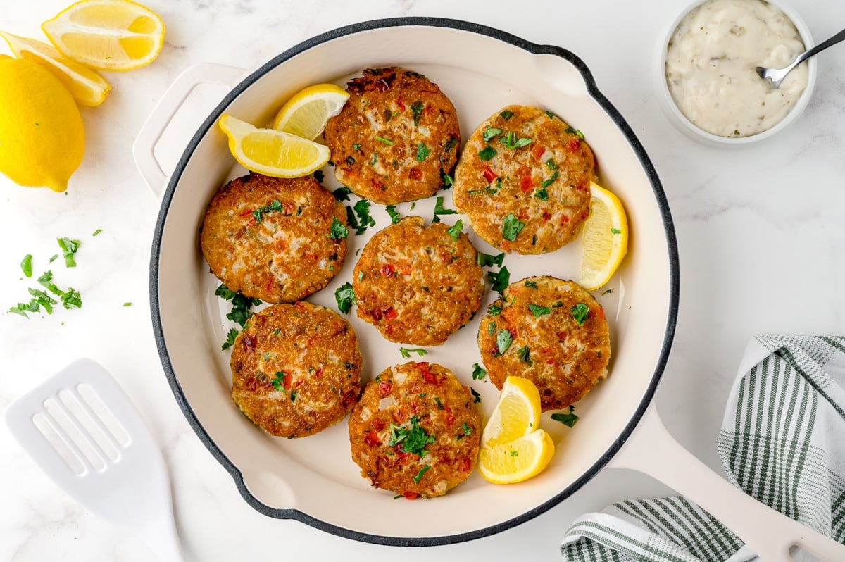 browned salmon patties in a white cast iron skillet