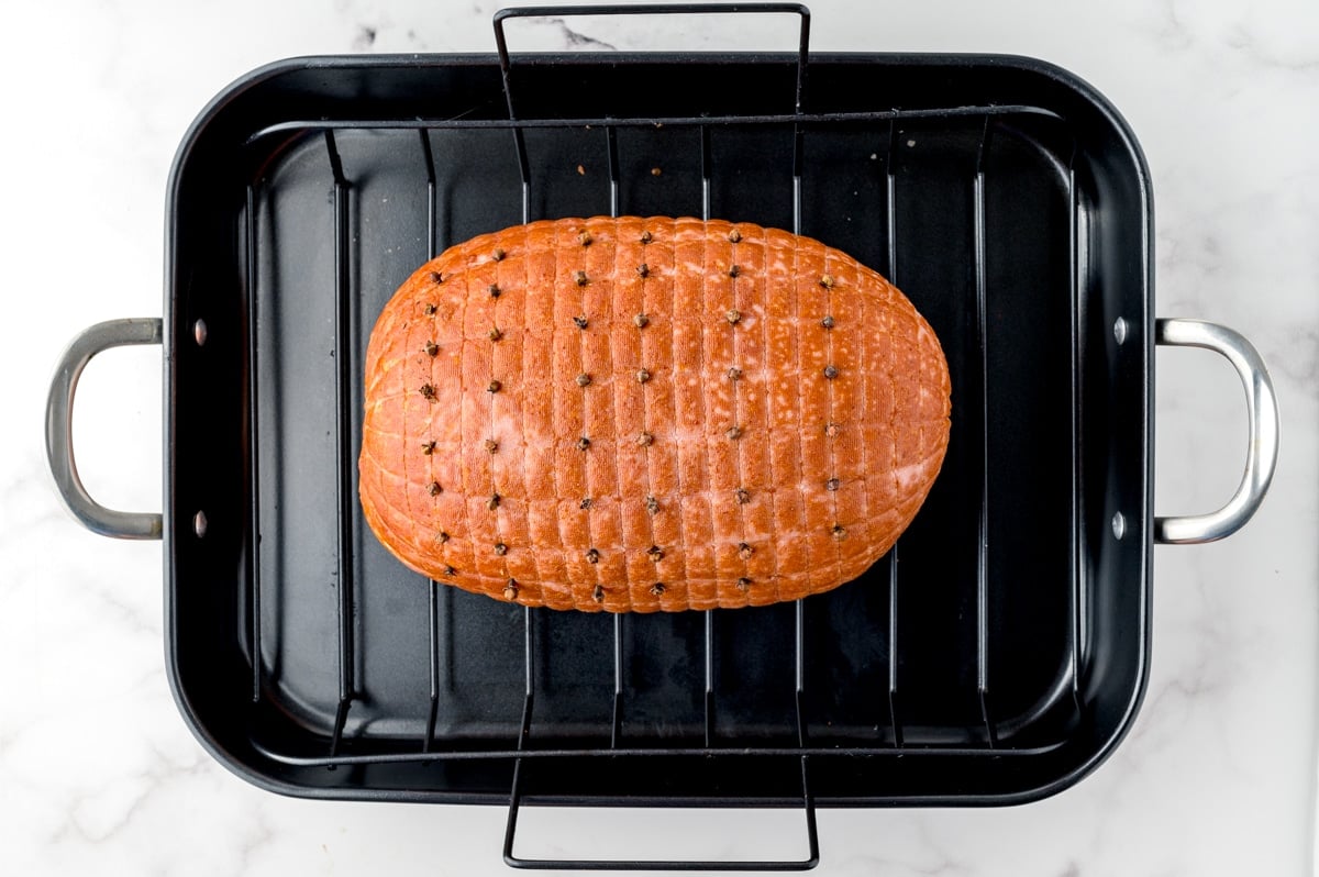 ham studded with cloves in a roasting pan