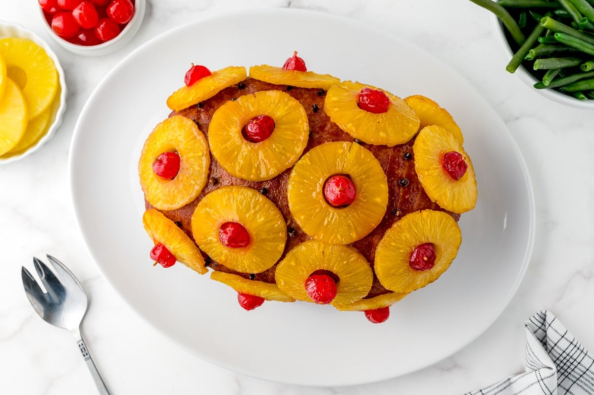 overhead of boneless ham roast with pineapples and cherries