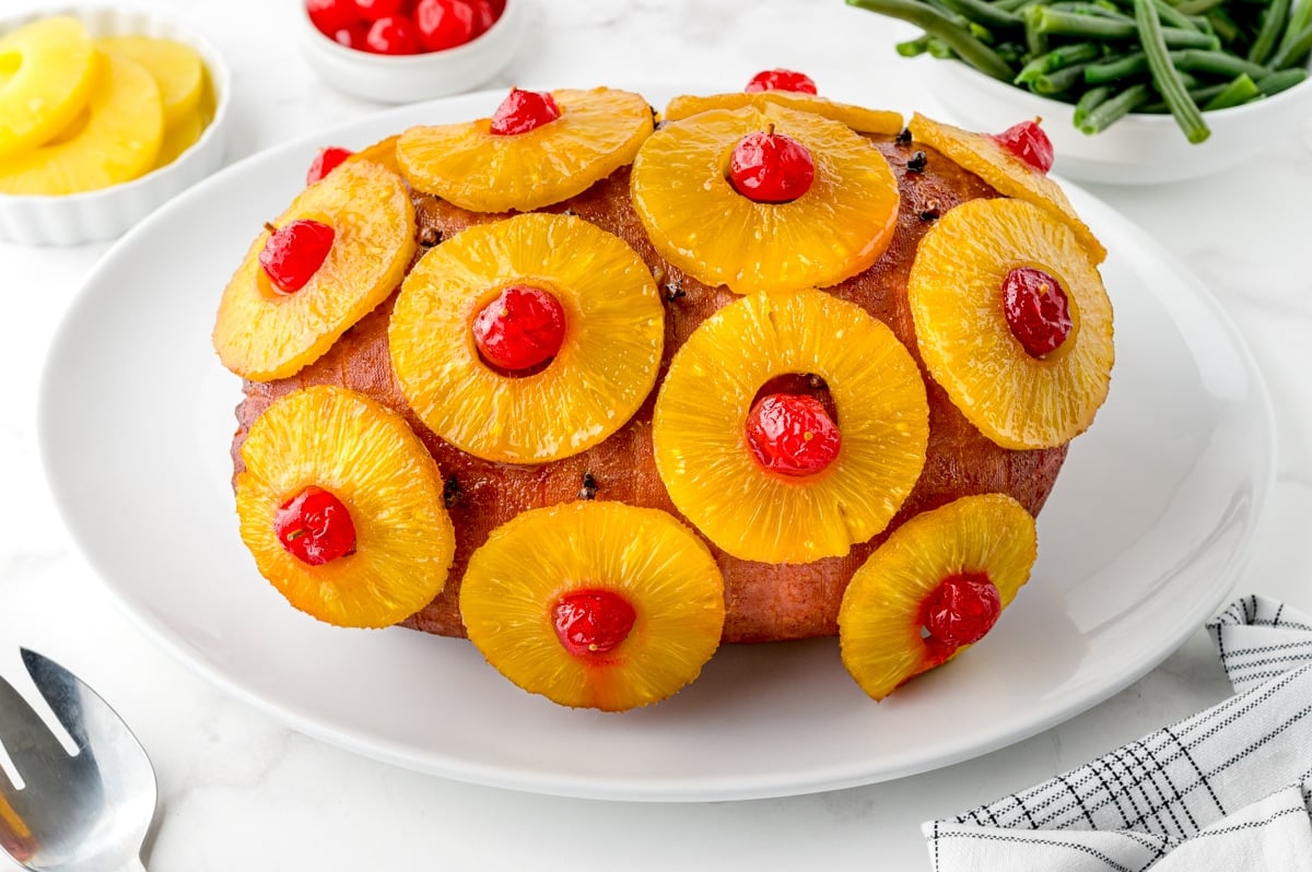 angle view of ham on a serving platter with green beans