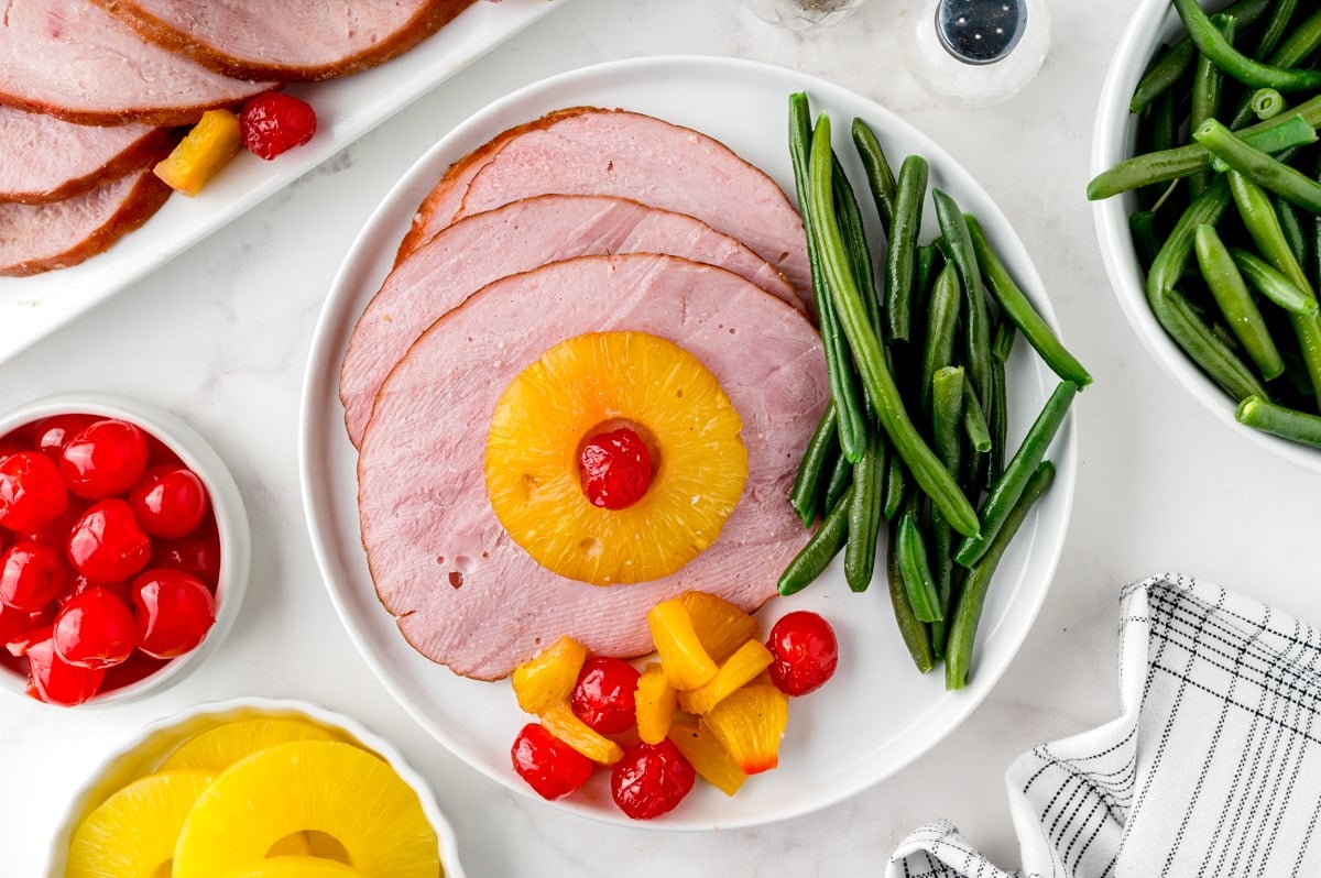 slices of ham with green beans on a dinner plate