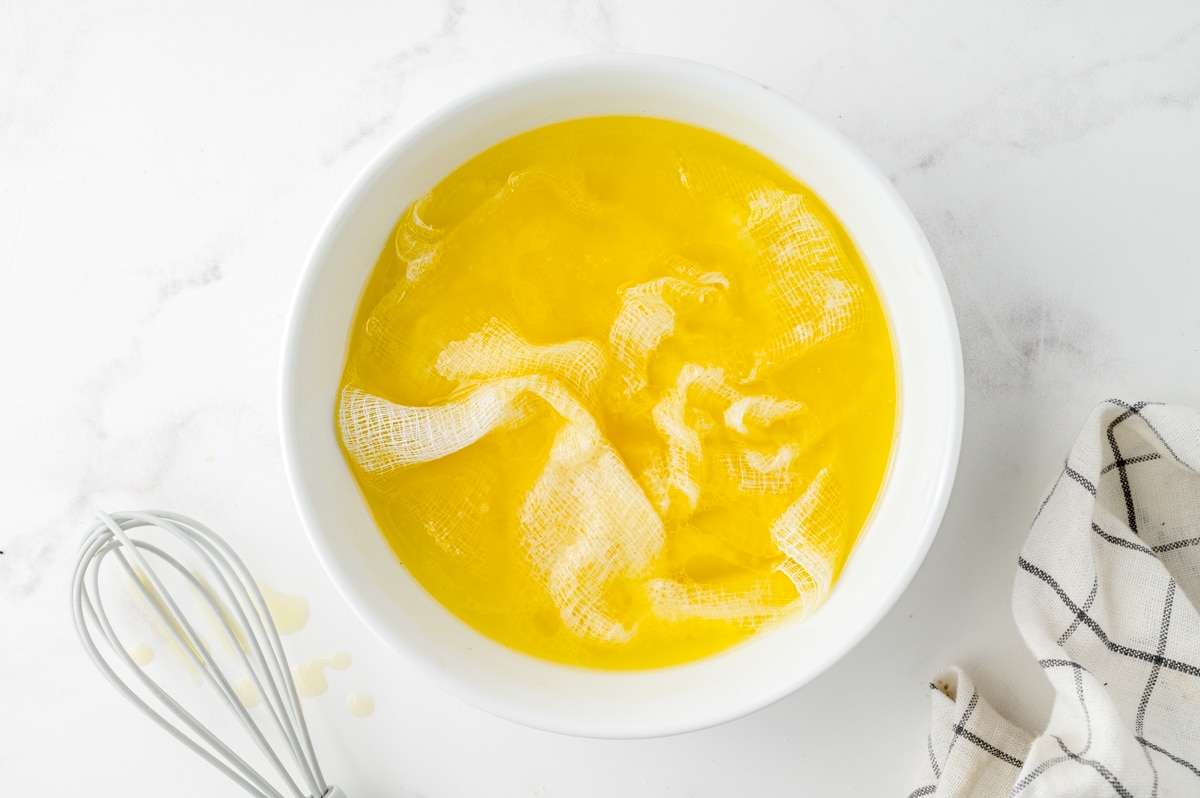 cheesecloth submerged in a bowl of butter