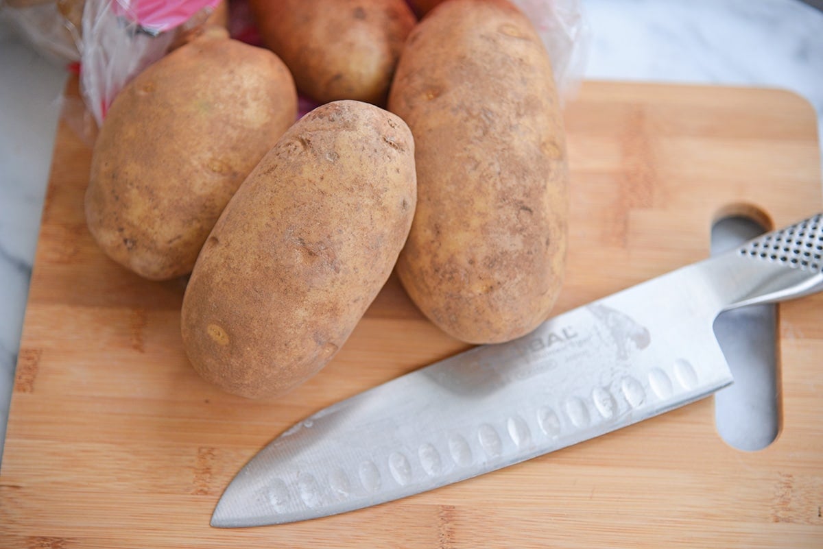 knife and whole potatoes on a cutting board