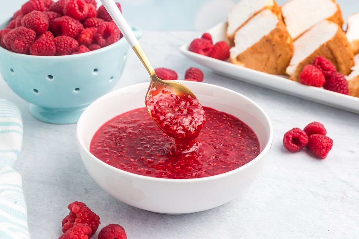 spoon dipping into bowl of raspberry sauce