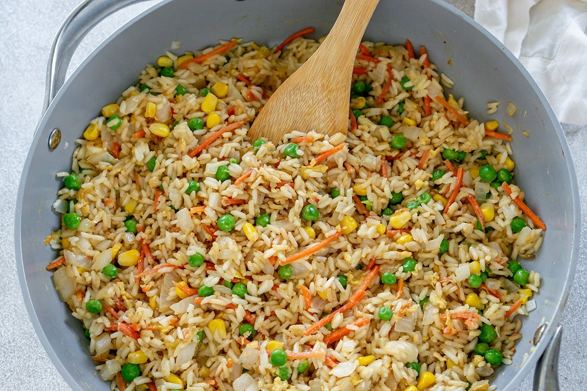 fried rice in pan with wooden spoon