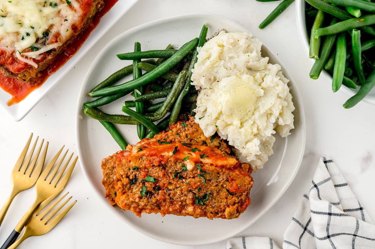 meatloaf on a plate with potatoes and green beans