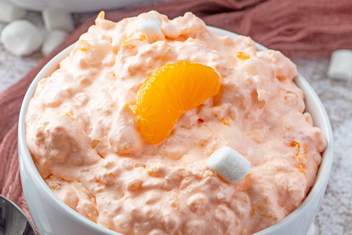 angle view of orange fluff salad in a white serving bowl