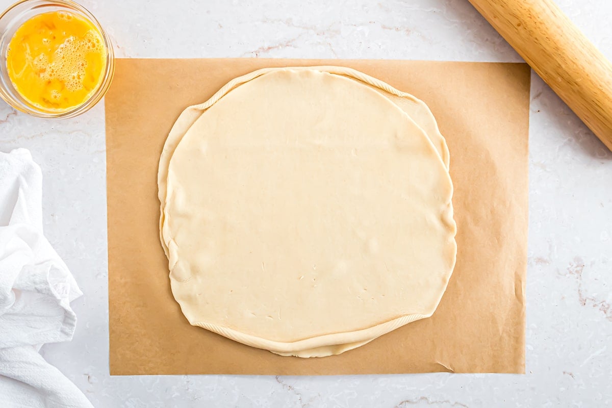 two layered pie crusts on a piece of parchments