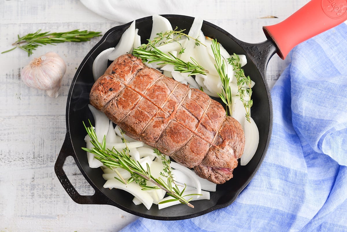 seared beef tenderloin in a pan with onions