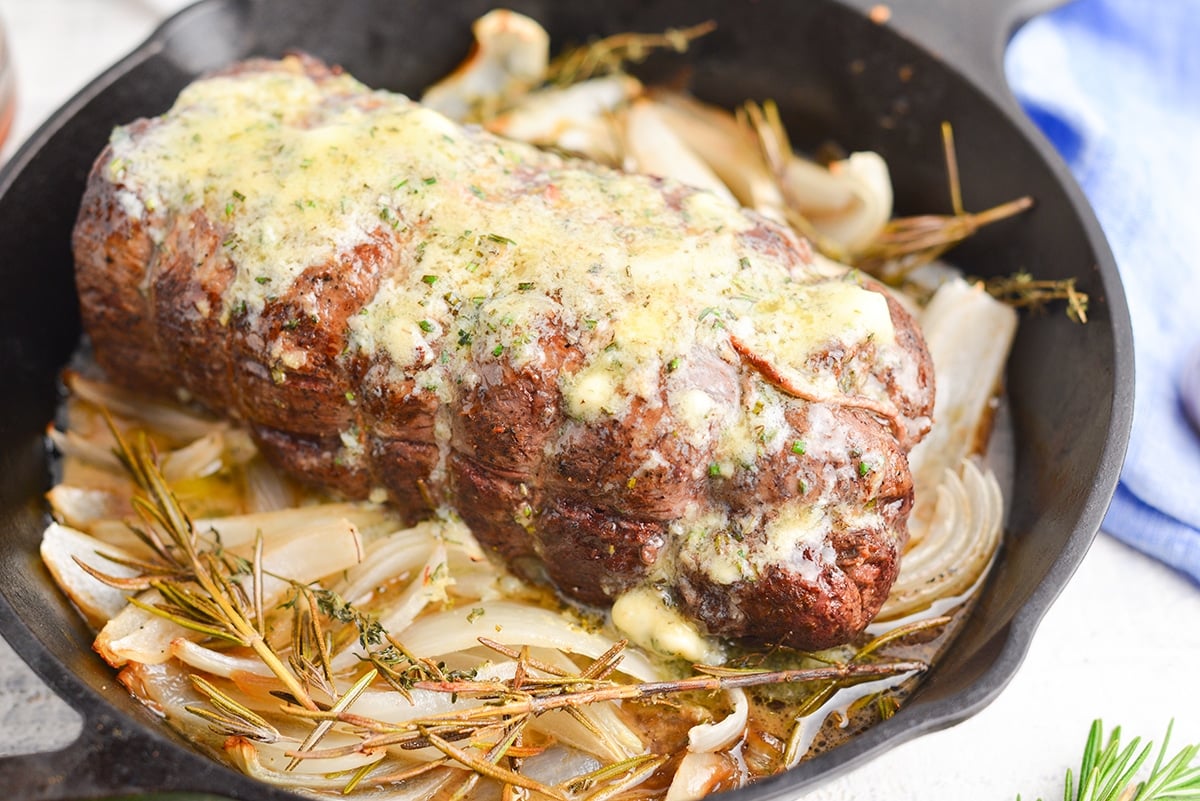 close up of beef tenderloin in a pan with onions