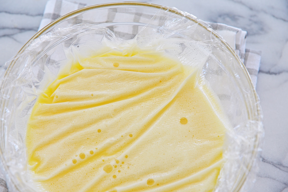 plastic wrap covering a bowl of warm custard