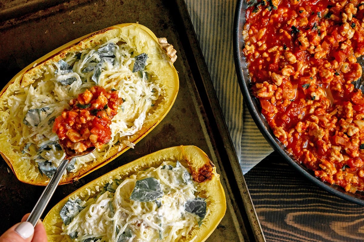 spooning sauce into spaghetti squash