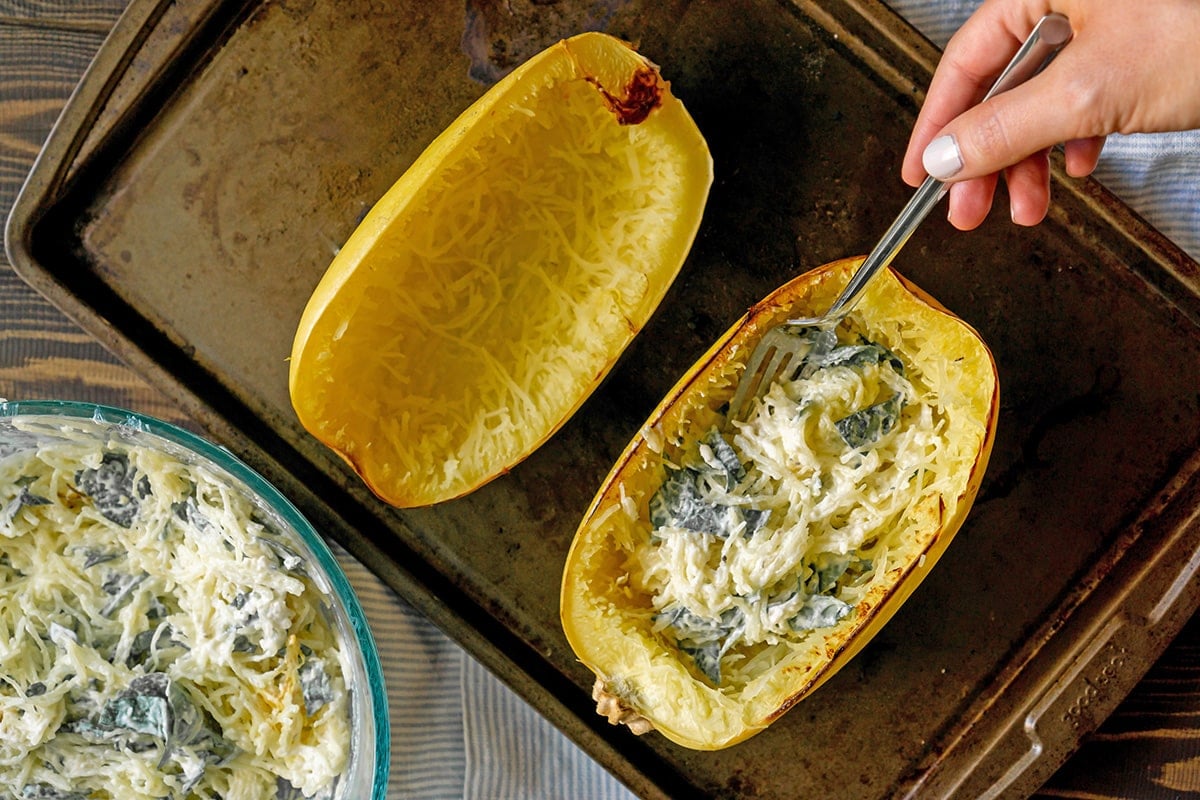 fork putting spinach filling into squash halves