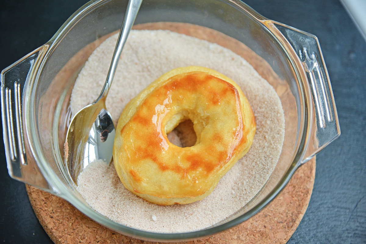 tossing a donut with cinnamon sugar