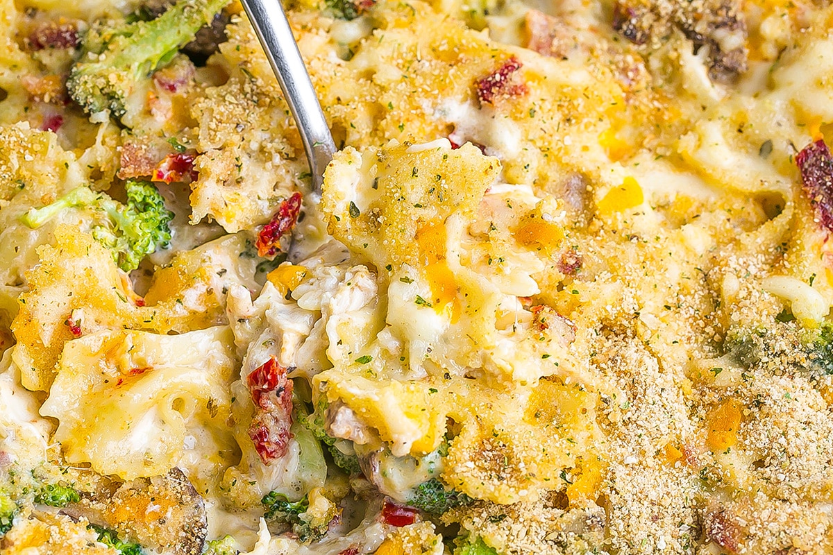 close up of a spoon in cheesy casserole with bowtie pasta